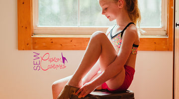 dancer sitting on stool looking down while putting on her dance shoe